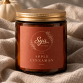 Vela Apple Cinnamon en frasco de vidrio ámbar con tapa dorada, sobre tela beige.