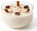 Arroz con Leche candle in a glass bowl, with a grain-like texture and brown stick- and star-shaped decorations.