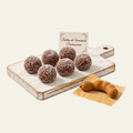 Brown Bolitas de Tamarindo wax melts with white speckles, arranged on a pale wooden board.