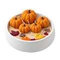 Vela Pumpkin Harvest de Sya en fuente blanca, con cinco calabazas naranjas y hojas de cera, sobre fondo transparente.