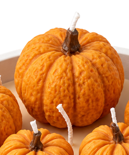 Close-up of the orange pumpkin shapes on the Pumpkin Harvest candle, showing textured ridges and wicks.