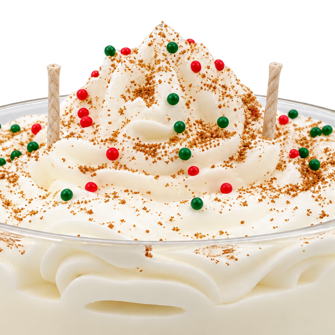 Close-up of the Tres Leches candle, showing cream-colored swirls, red and green decorations, and wicks.