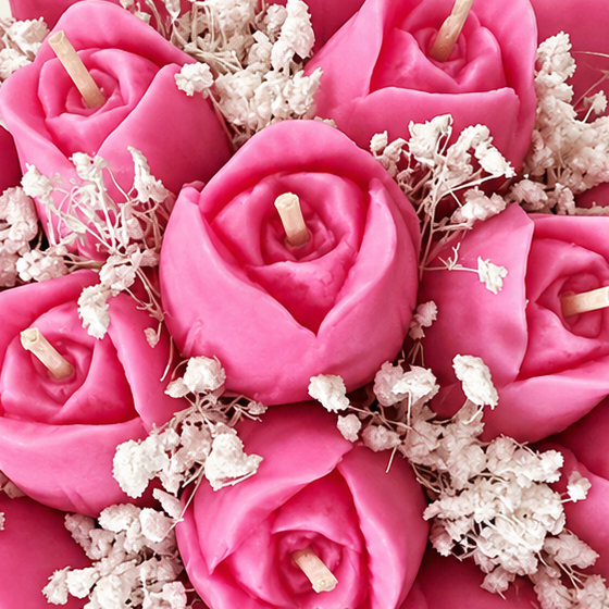 Close-up of pink flower-shaped Tulip Bouquet candles with visible wicks and small white flowers.
