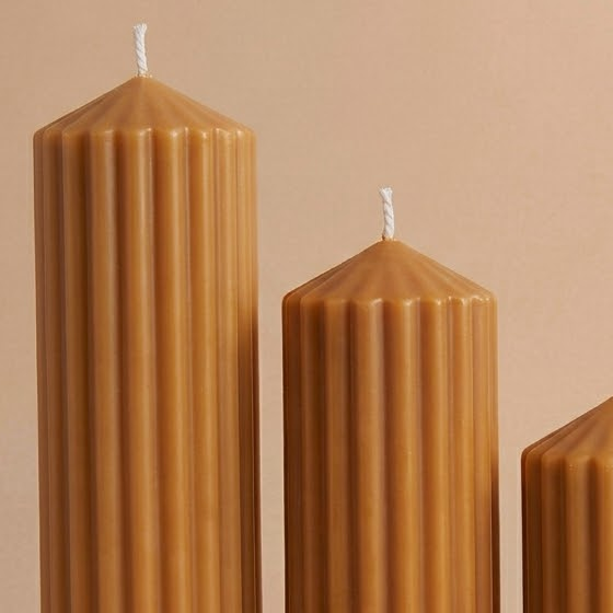Close-up of caramel-colored Elegance Heights candles with vertical ribs, pointed tops and visible wicks.