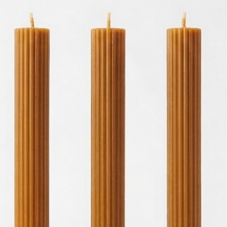 Close-up of caramel-colored Linear Elegance candle tops, showing vertical ribs and wicks.